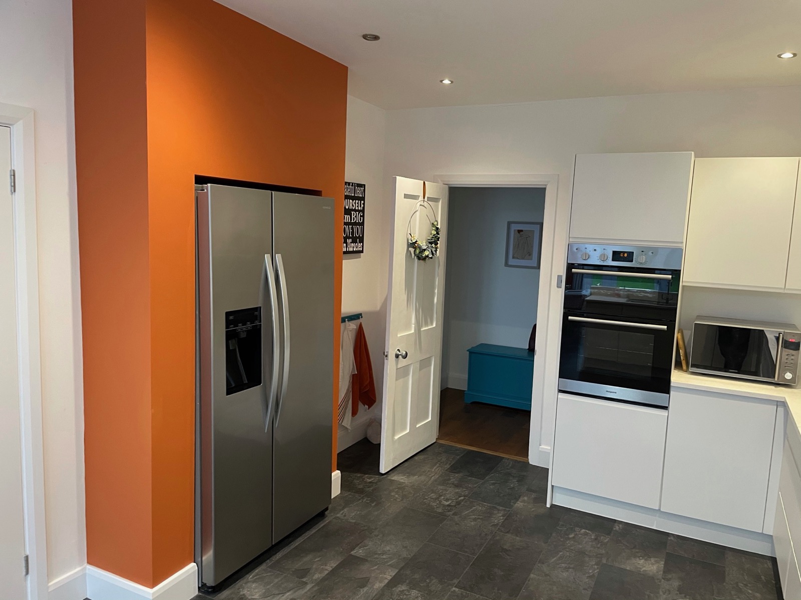 Kitchen white orange accent wall fridge freezer, made and fitted by Sussex Design Interiors