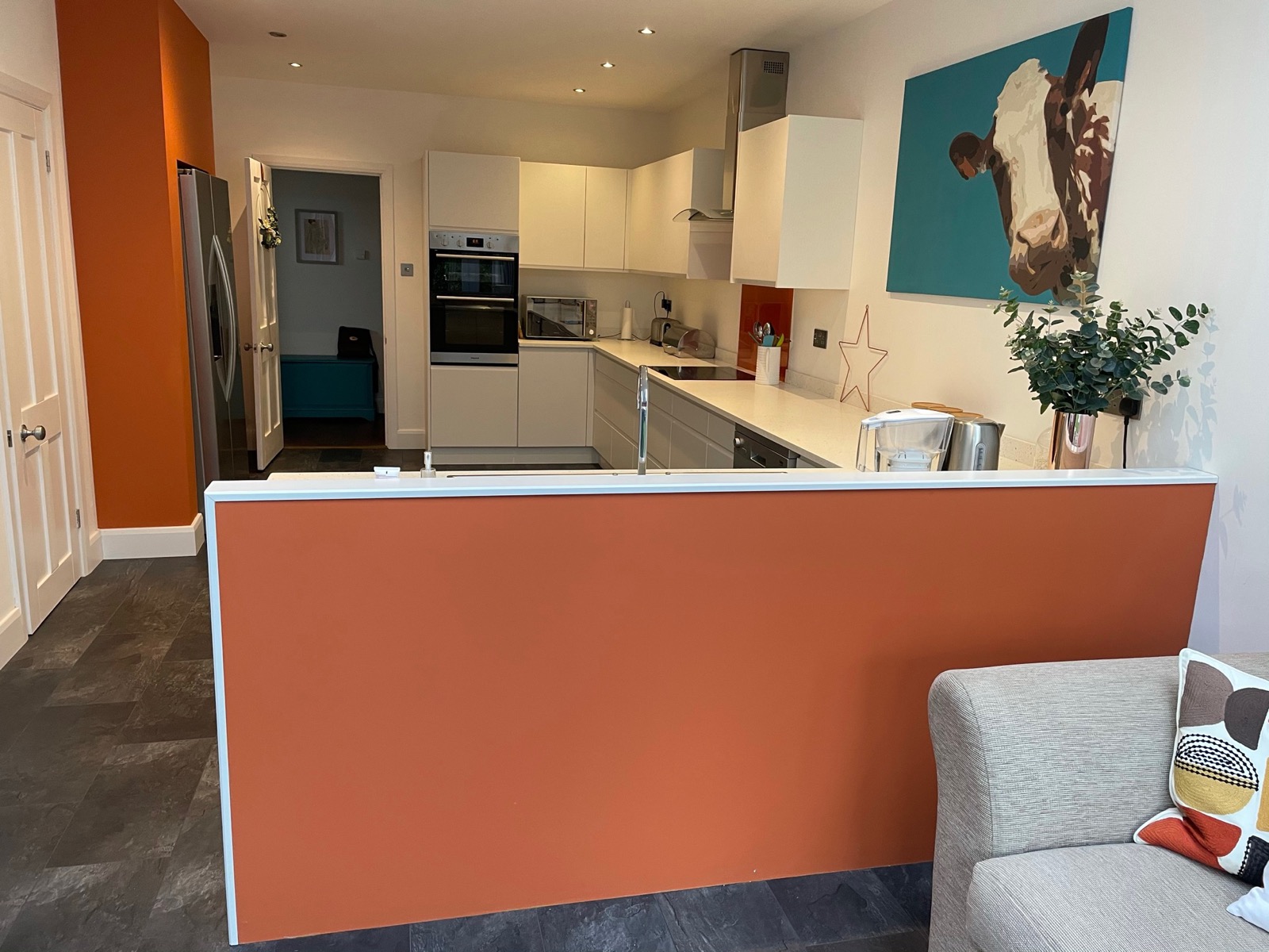 Kitchen white orange wall open plan artwork, made and fitted by Sussex Design Interiors