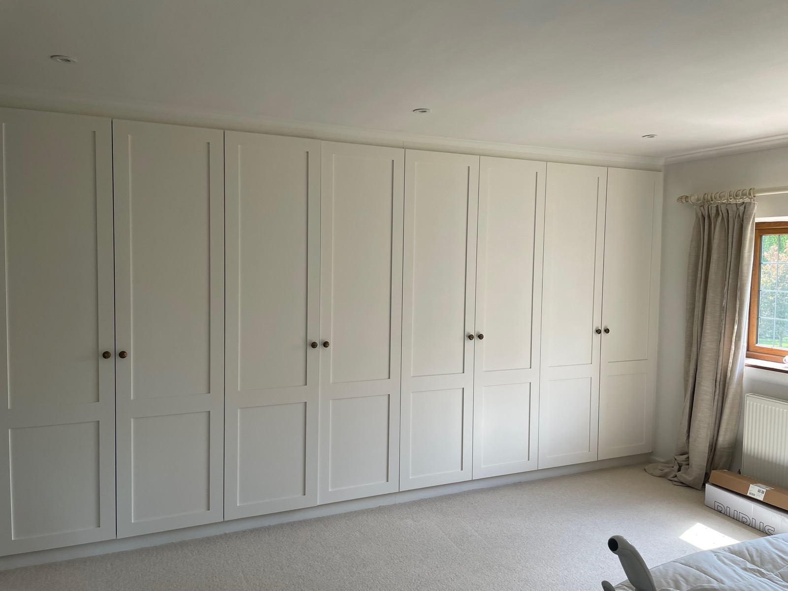 White shaker fitted wardrobes running wall to wall in a bedroom